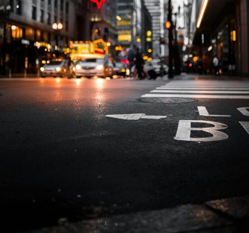 Dynamic cityscape at night with illuminated signs, streetlights, and a bustling intersection.